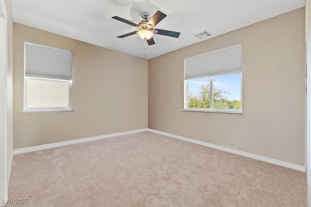 carpeted spare room featuring ceiling fan, baseboards, and visible vents