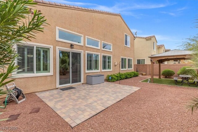 back of property with stucco siding, a gazebo, fence, and a patio