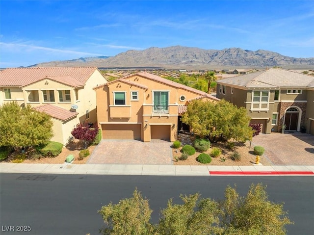 mediterranean / spanish home with an attached garage, driveway, a balcony, stucco siding, and a tiled roof