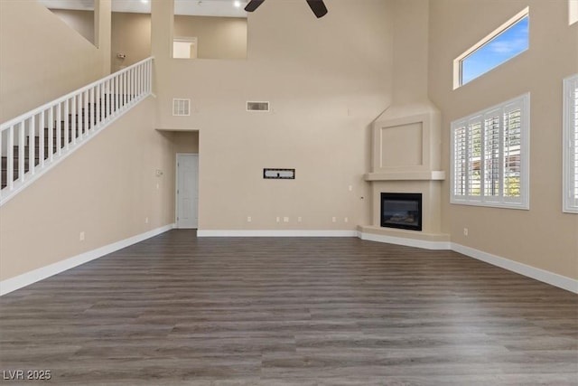 4212 Hawks Glide Ave, North Las Vegas, NV 89084 - unfurnished living room with a towering ceiling, ceiling fan, dark wood-type flooring, a glass covered fireplace, and stairway