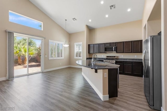 4212 Hawks Glide Ave, North Las Vegas, NV 89084 - kitchen with appliances with stainless steel finishes, high vaulted ceiling, wood finished floors, dark stone counters, and a center island with sink