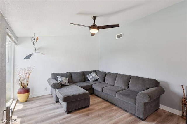 living room with light wood-style flooring, baseboards, a ceiling fan, and visible vents