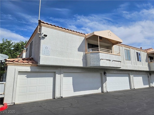 8452 Boseck Dr Unit 216, Las Vegas, NV 89145 - rear view of house with a garage, a tiled roof, stucco siding, and a balcony