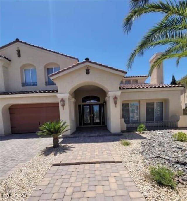 view of front of property with french doors, a garage, stucco siding, and decorative driveway
