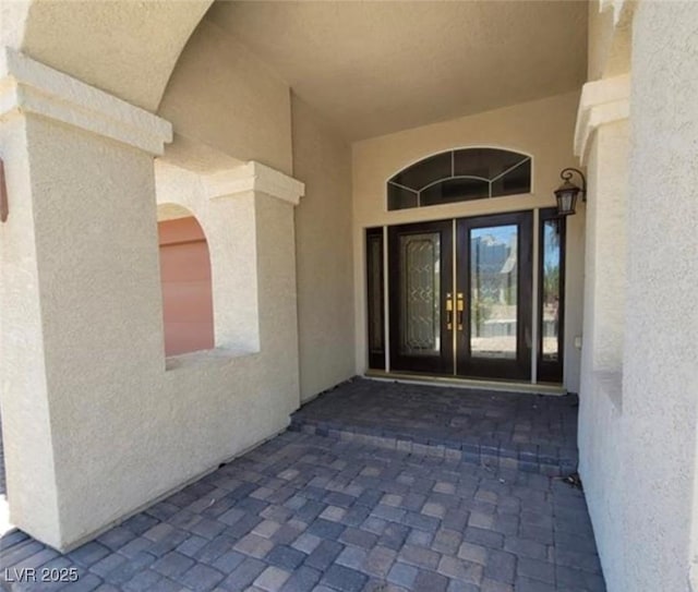 view of exterior entry featuring stucco siding and french doors