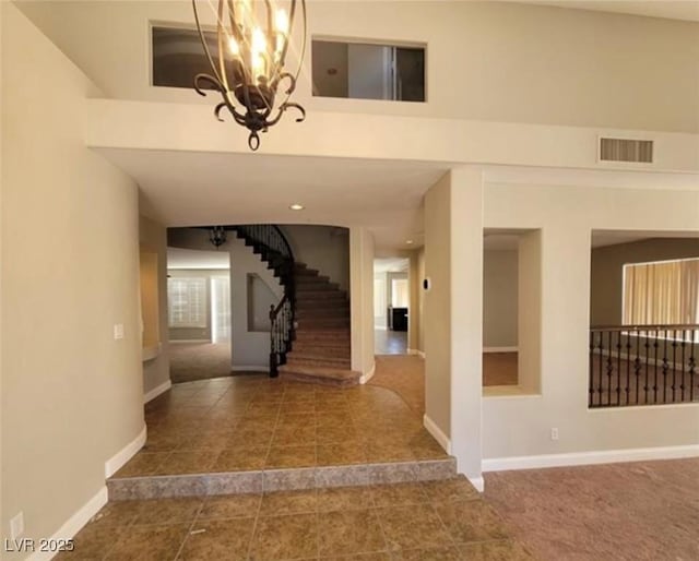 entryway with visible vents, baseboards, a notable chandelier, stairway, and tile patterned floors