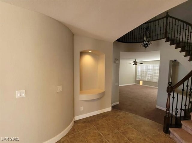 corridor with tile patterned floors, baseboards, carpet, and stairs