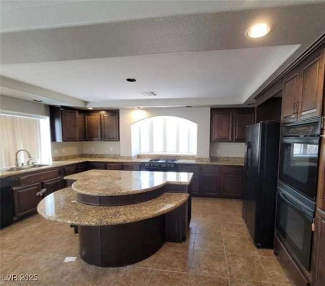 kitchen featuring a center island, a sink, black appliances, and a healthy amount of sunlight