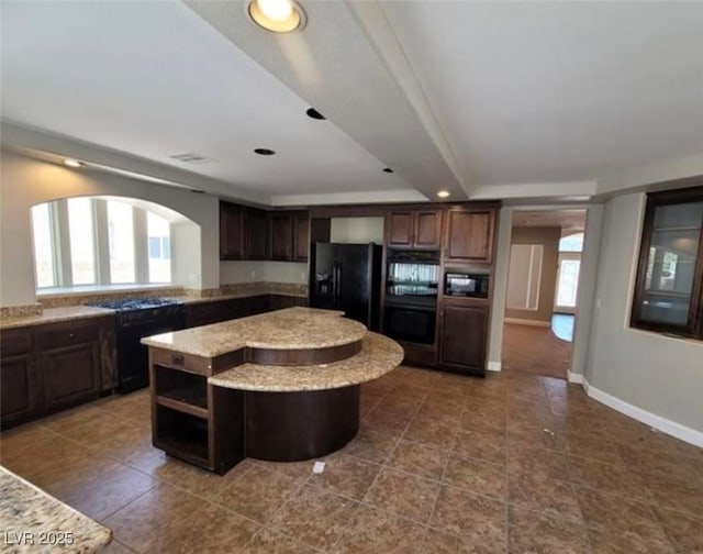 kitchen with dark brown cabinets, tile patterned floors, a center island, and black appliances