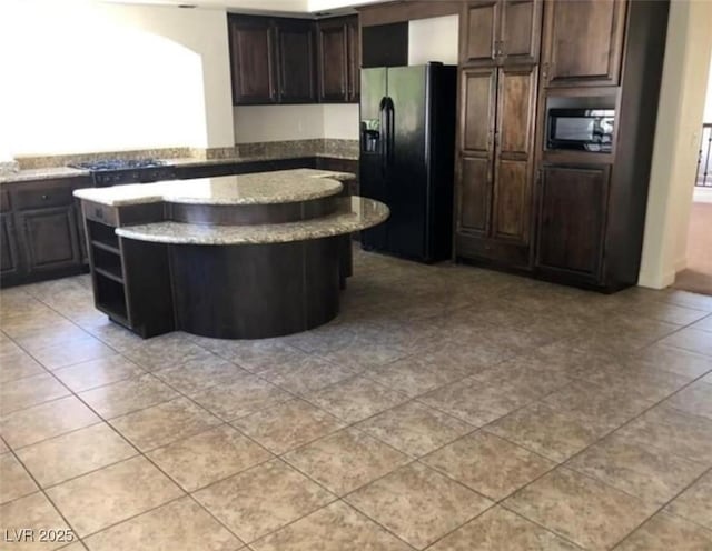 kitchen with open shelves, dark brown cabinets, black appliances, a kitchen island, and light stone counters