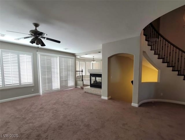unfurnished living room featuring ceiling fan, carpet, arched walkways, visible vents, and baseboards