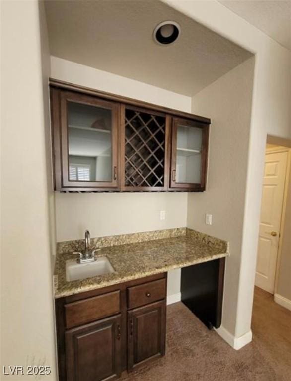 bar with baseboards, dark colored carpet, a sink, and wet bar