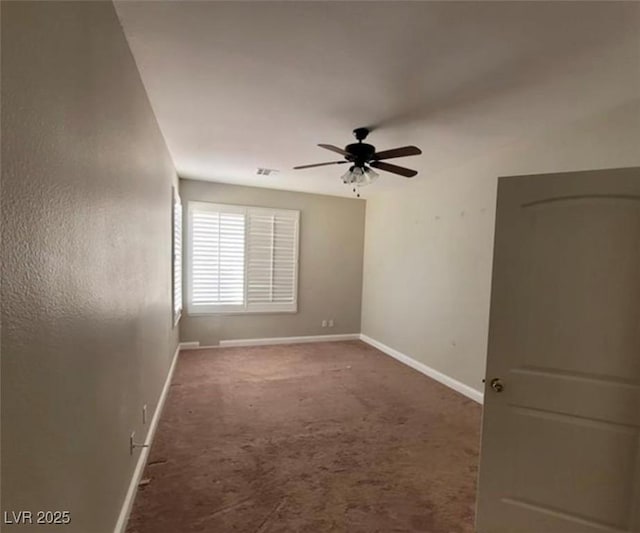 carpeted empty room featuring baseboards, a ceiling fan, and visible vents