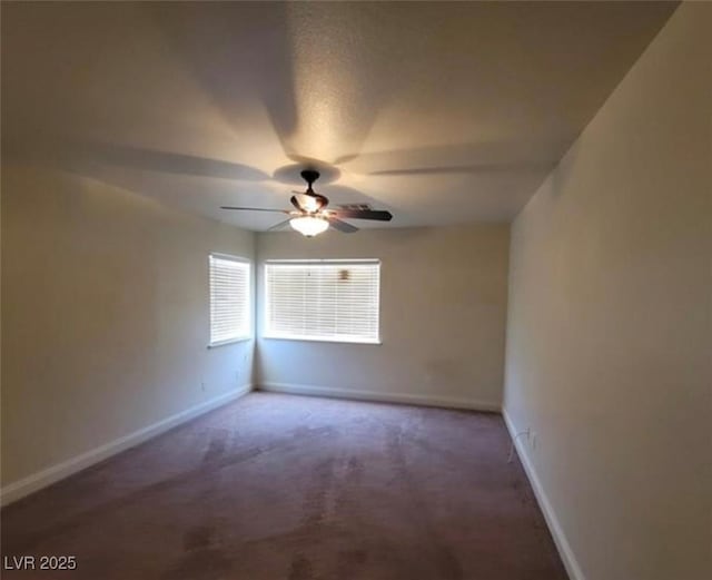 carpeted spare room with ceiling fan and baseboards