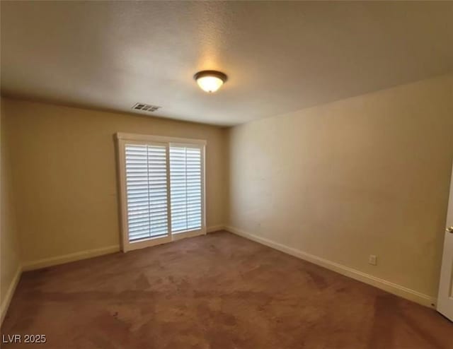 unfurnished room with carpet, visible vents, and baseboards