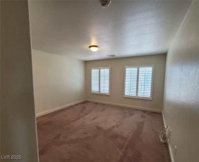 carpeted spare room featuring a textured ceiling, baseboards, and visible vents
