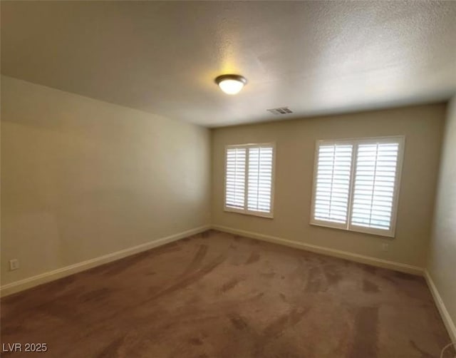 spare room with a textured ceiling, baseboards, carpet, and visible vents