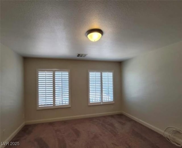 carpeted spare room with visible vents, baseboards, and a textured ceiling