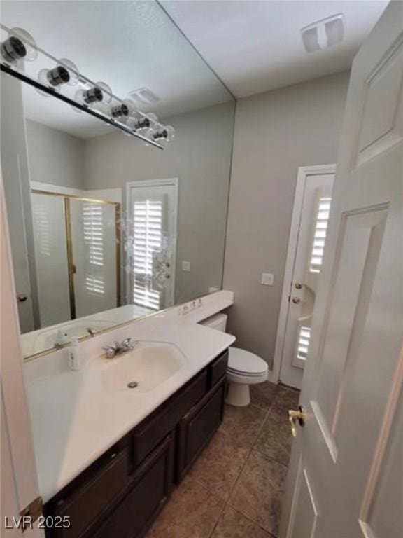 bathroom featuring vanity, tile patterned floors, toilet, a shower stall, and visible vents