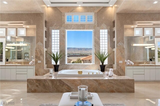 5020 Spanish Heights Dr, Las Vegas, NV 89148 - bathroom with marble tiled floors, two vanities, a garden tub, tile walls, and recessed lighting