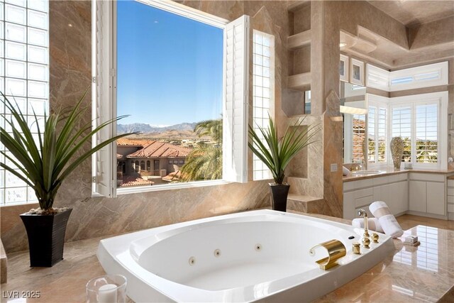 5020 Spanish Heights Dr, Las Vegas, NV 89148 - bathroom with a jetted tub, a mountain view, a sink, and marble tiled flooring