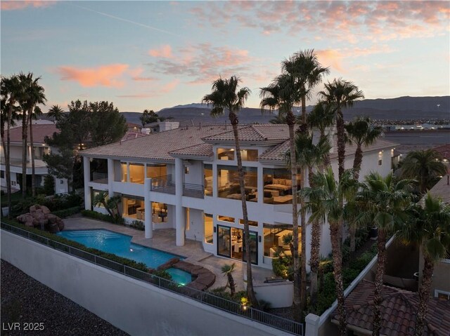 5020 Spanish Heights Dr, Las Vegas, NV 89148 - back of property at dusk featuring a balcony, a fenced backyard, a patio area, a tile roof, and stucco siding
