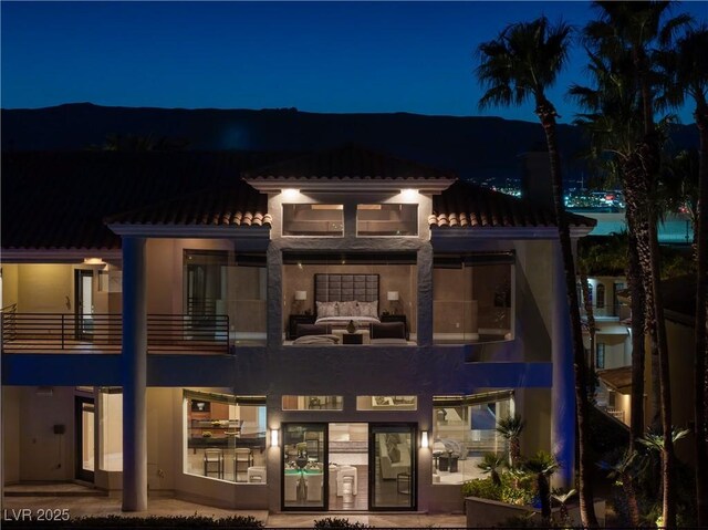 5020 Spanish Heights Dr, Las Vegas, NV 89148 - back of house at twilight with a tile roof, stucco siding, and an outdoor living space