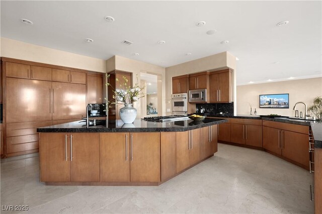5020 Spanish Heights Dr, Las Vegas, NV 89148 - kitchen featuring stainless steel appliances, a sink, brown cabinetry, a spacious island, and recessed lighting