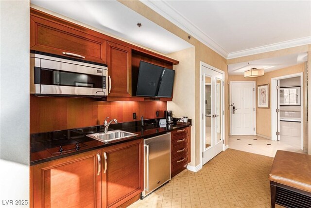 145 E Harmon Ave Unit 2019, Las Vegas, NV 89109 - kitchen with stainless steel microwave, crown molding, dark countertops, brown cabinetry, and a sink