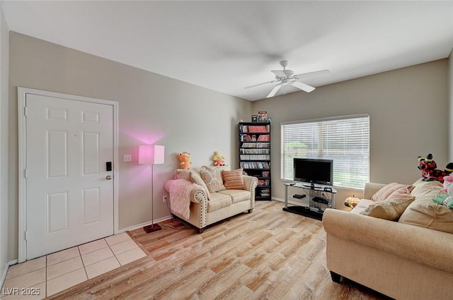 living area featuring light wood-style floors, baseboards, and a ceiling fan