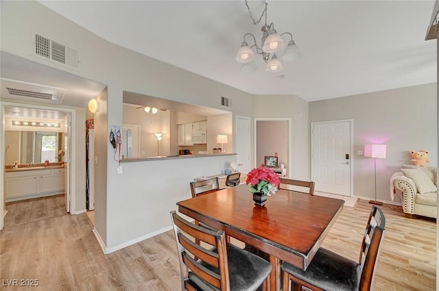 dining room with visible vents, baseboards, light wood finished floors, and an inviting chandelier