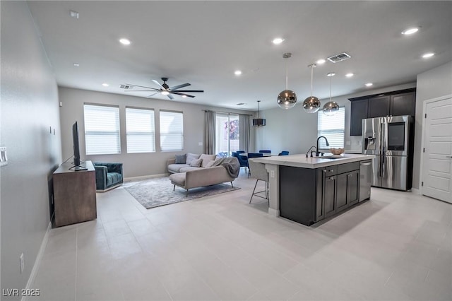 kitchen featuring visible vents, a sink, stainless steel appliances, open floor plan, and a breakfast bar area