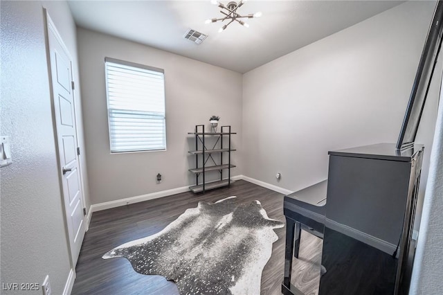 office area featuring dark wood-style flooring, visible vents, baseboards, and a notable chandelier