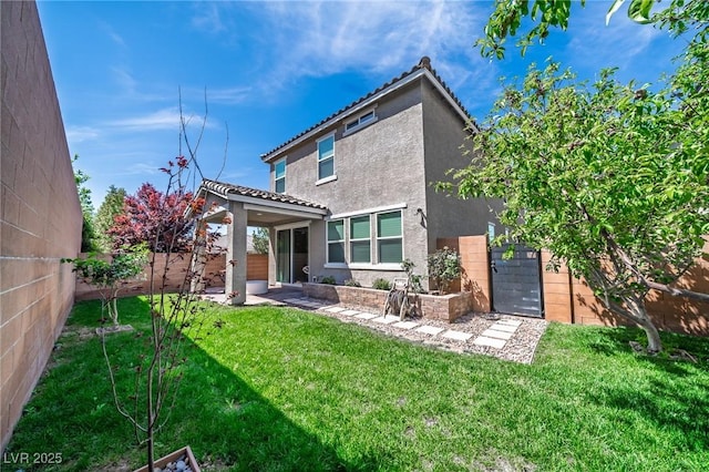rear view of house with a yard, a fenced backyard, a tile roof, and stucco siding