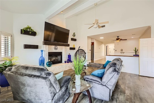 living room featuring high vaulted ceiling, a ceiling fan, wood finished floors, a fireplace, and recessed lighting