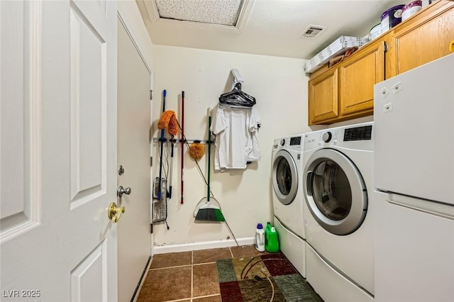 clothes washing area with washing machine and clothes dryer, baseboards, visible vents, cabinet space, and dark tile patterned flooring