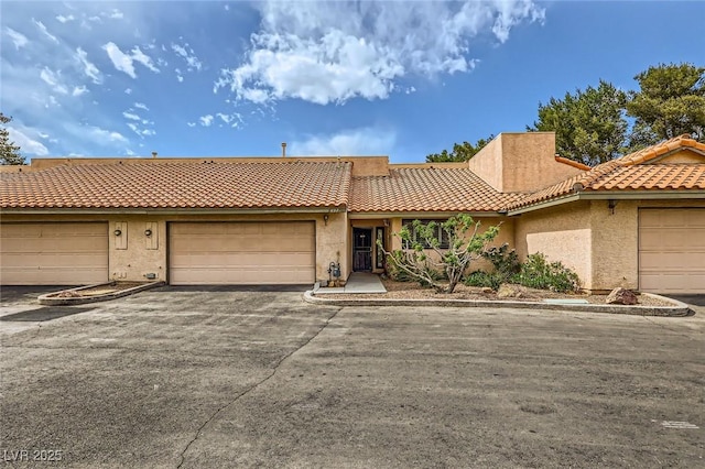 multi unit property featuring a tile roof, aphalt driveway, and stucco siding
