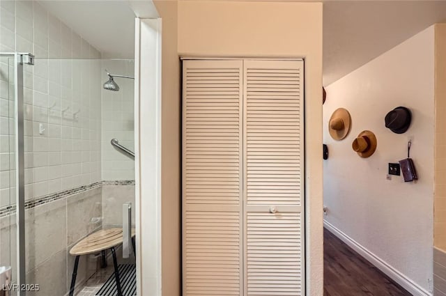 full bathroom featuring a closet, wood finished floors, and a stall shower