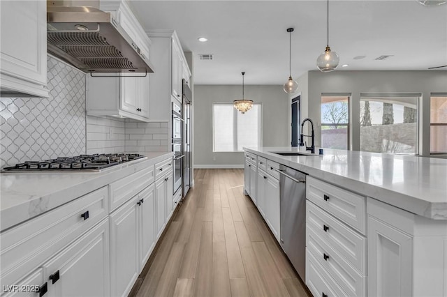 2805 Proust Ct, Henderson, NV 89044 - kitchen featuring extractor fan, appliances with stainless steel finishes, light wood-type flooring, white cabinetry, and decorative backsplash