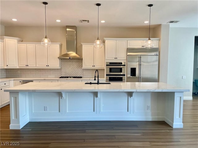 2805 Proust Ct, Henderson, NV 89044 - kitchen with stainless steel appliances, wall chimney range hood, white cabinets, decorative backsplash, and recessed lighting