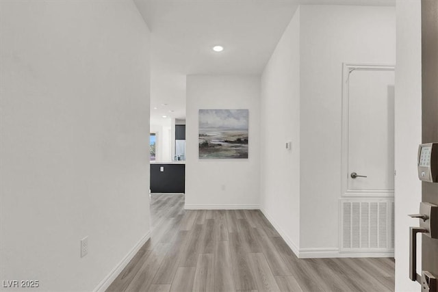 hallway featuring light wood finished floors, baseboards, visible vents, and recessed lighting