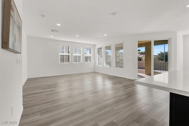 unfurnished living room featuring baseboards, light wood-style floors, visible vents, and recessed lighting