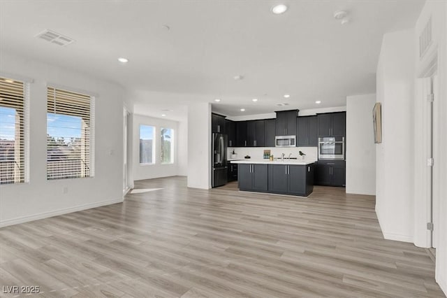 kitchen with open floor plan, light countertops, visible vents, dark cabinetry, and appliances with stainless steel finishes