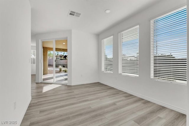 spare room featuring baseboards, visible vents, and light wood-style flooring