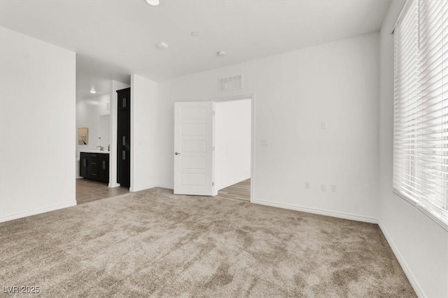 empty room with baseboards, visible vents, light colored carpet, and a healthy amount of sunlight