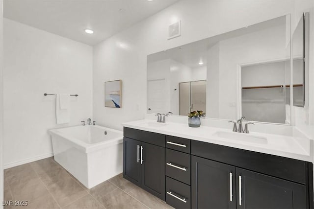 full bath featuring a soaking tub, a sink, tile patterned flooring, and double vanity