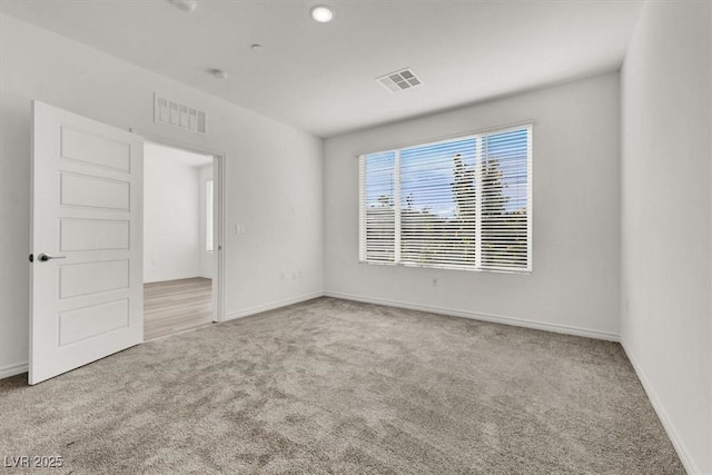 carpeted spare room featuring baseboards, visible vents, and recessed lighting