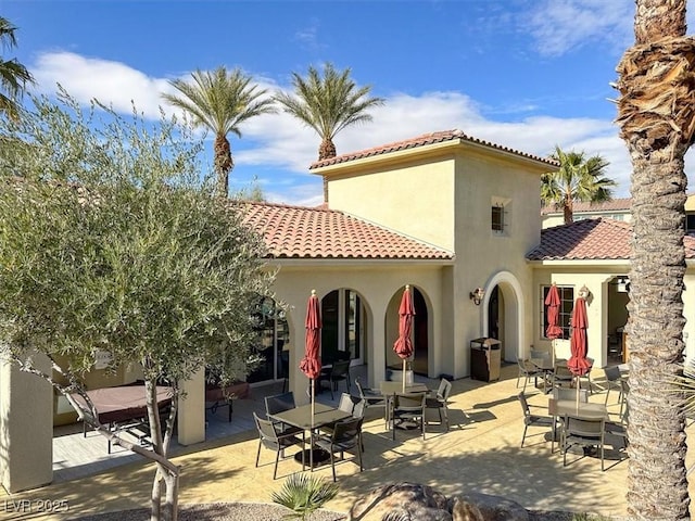 back of property with stucco siding, a patio, and a tiled roof