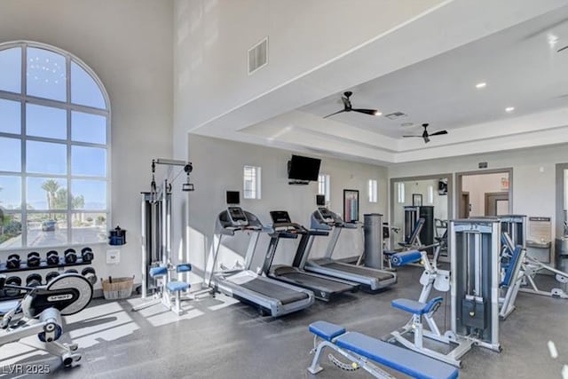 gym with a ceiling fan, visible vents, and a raised ceiling