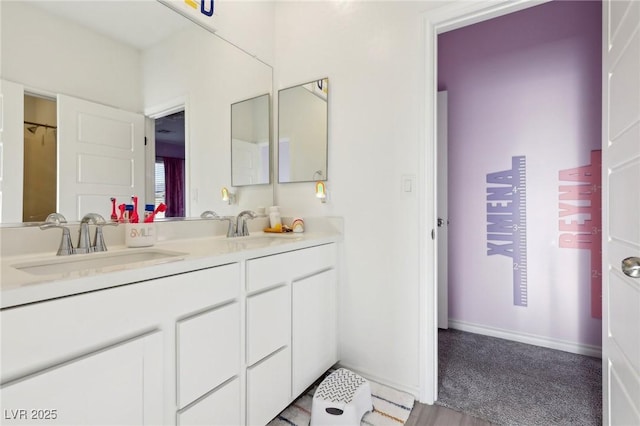 bathroom with double vanity, baseboards, and a sink